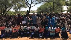 Picture of the teachers and pupils in the school, taken outside under tress.