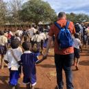 Picture of child with an adult and other children walking towards a school.